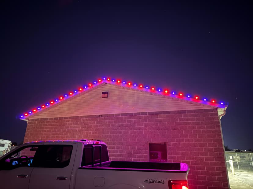 Building exterior with festive red and blue lights along the roofline at night.